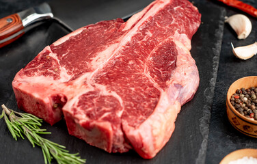 Raw Porterhouse or T-bone beef meat Steak with herbs on stone background