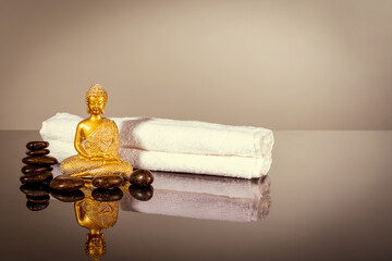Golden Buddha with towels and stones for massage as a concept of SPA meditation, harmony of soul and body, finding peace of mind
