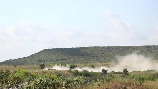 Military vehicle moving though training ground, wide view