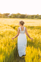 beautiful young woman with summery long dress walking in the field