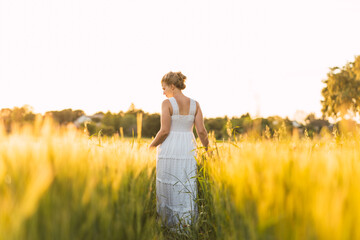 beautiful young woman with summery long dress walking in the field