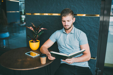 Pensive man reading book during coffee break