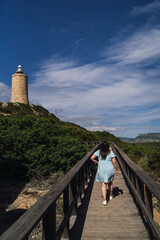 Chica guapa joven posando alegremente junto a un faro en la costa de andalucia