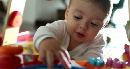 Cute baby playing with toy indoors. Close-up adorable child plays touching object with hand
