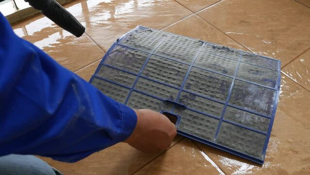A maintenance technician is inspecting and cleaning the air conditioning system installed in the home.