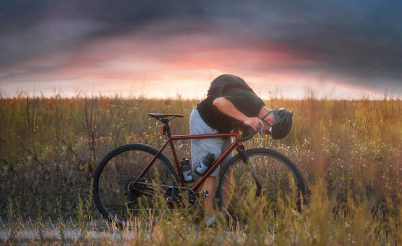 Cyclist in the field checking up his front wheel. Adventures on bicycle.