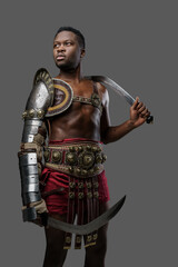 Obraz premium Portrait of isolated on gray gladiator of african descent dressed in light armor holding two swords.