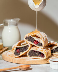 Pouring honey on piece of poppy seed strudel