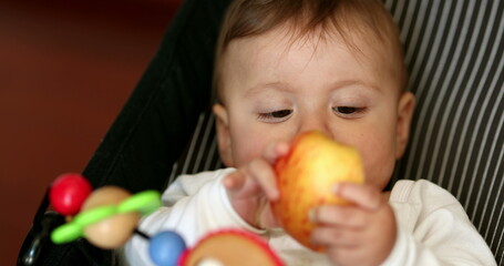Fototapeta na wymiar Cute baby eating healthy snack, infant child eats piece apple