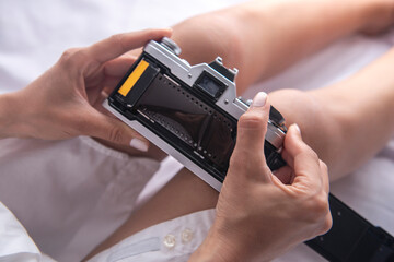 young woman placing roll of film on analog camera
