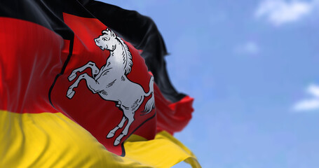 The flag of Lower Saxony waving in the wind on a clear day. - obrazy, fototapety, plakaty