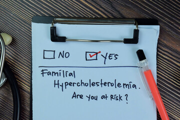 Familial Hypercholesterolemia, Are you at Risk? Yes write on a paperwork isolated on Wooden Table.