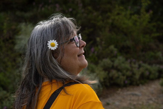 white-haired woman wearing glasses with a daisy in her hair