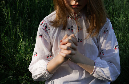 A girl in Ukrainian embroidered shirt is praying