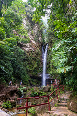 Stone staircase with a view of a paradisiacal natural waterfall in the middle of the jungle.