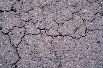 Old worn and cracked asphalt with cracks. Asphalt cracked road dark texture.