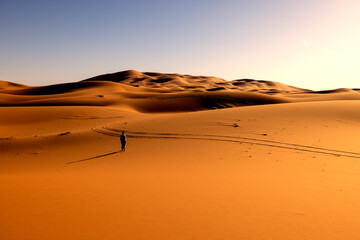 Hombre con chilaba azul caminando por el desierto del Sahara