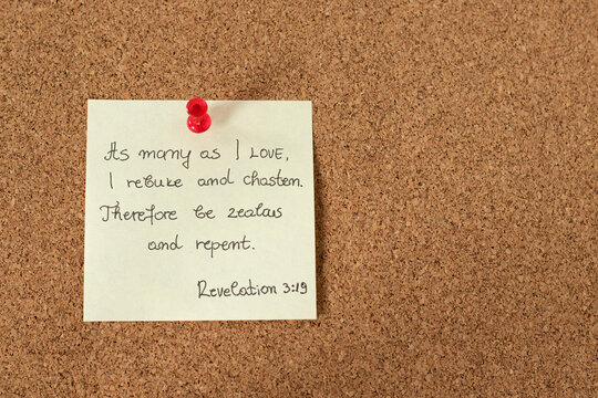 A handwritten verse note from the Holy Bible Book of Revelation 3: 19 on a pinning board. Jesus Christ's call to repentance. Christian biblical concept. Top view. Close-up.