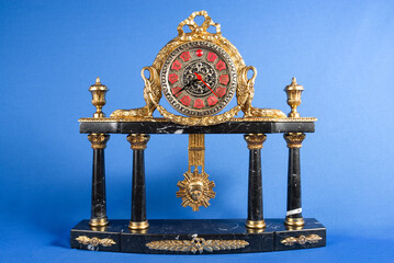 vintage bronze watch on a blue background, bronze fireplace clock with a pendulum, golden old desktop clock on a blue background, antique clock of marble and bronze, antique bronze clock 