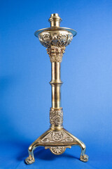 classic bronze chandelier on a blue background, ancient candlestick studio photo, antique candlestick isolated, brass chandelier, one vintage candlestick, bronze candle tree on blue background