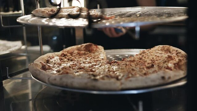 The seller takes a slice of pizza from a rotating shelf for sale. Shooting in close-up