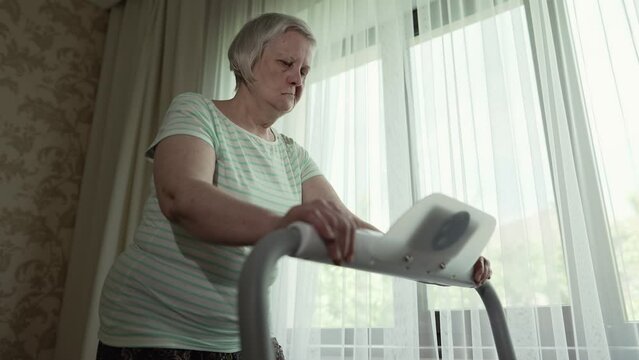 Woman walks on a treadmill in a front of the window