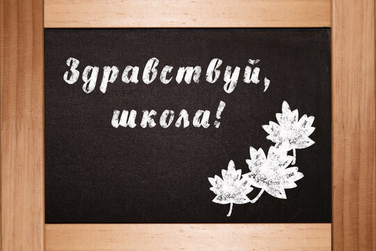 The concept of the beginning of the school year. On the black black blackboard in chalk is written in Russian language Hello school - Powered by Adobe