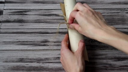 Treasure map on a wooden background. A woman's hands unfold a scroll with an ancient pirate map.