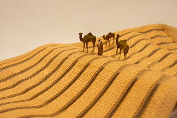 Fototapeta na wymiar The Traveller and His Camels on The Desert of Sahara. Miniature Photo Concept
