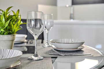 Table settings for dinner with empty wine glasses, plates on place mat