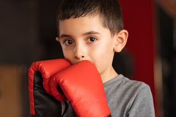 close up portrait of a boy wearing red boxing gloves