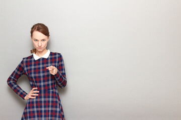 Portrait of serious young woman pointing with index finger at you
