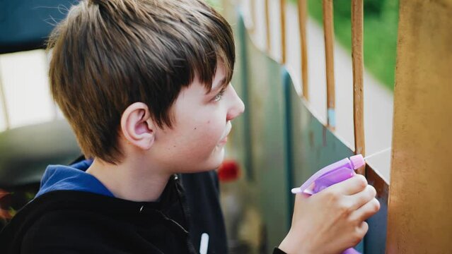 A boy dabbling splashes water from a sprayer from the balcony. Cool close-up shots