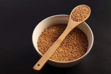 Semillas de lino en un cuenco con una cuchara de madera