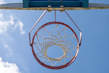 Close-up of a basketball hoop seen from below, blue sky in the background