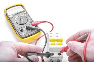 a man takes a voltage measurement with a multimeter on a circuit breaker