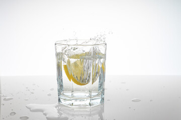 water splashes in a glass from falling lemon slices into it