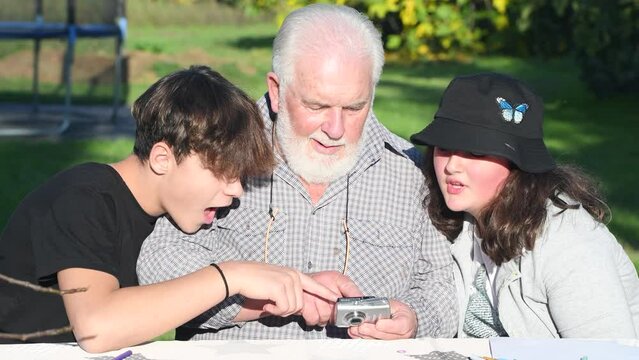 Man reviewing camera pictures outdoor with his grandchildren