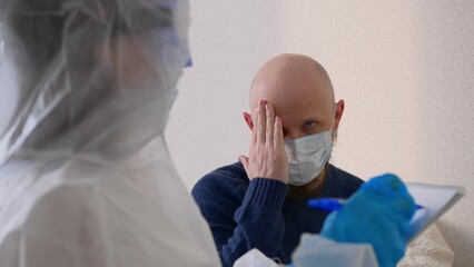 A middle-aged man in a mask sits at the doctor's office and complains of a sore throat and...
