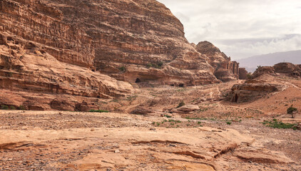 Typical landscape at Petra, Jordan, red dusty ground, small green plants, Ad Deir - Monastery -...