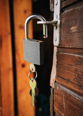 Classic metal padlock hanging at old wooden cottage, keys inside, closeup detail