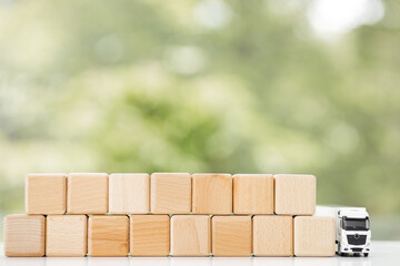 Flat lay composition of toy truck with wooden cubes on green background. Logistics and wholesale concept