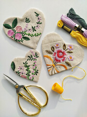 Fabric linen hearts with floral embroidery and vintage scissors, needle, thread on white, flat lay