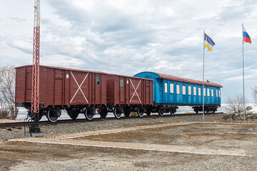 Fototapeta na wymiar Blue passenger and two freight cars on the shore of Lake Baikal