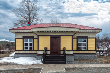 House with a red tin roof, finished with yellow wooden clapboard