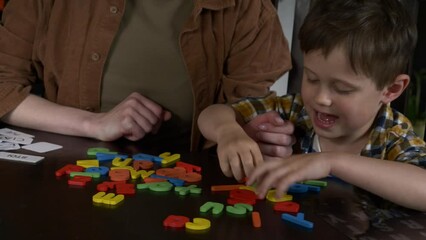Mom teaches her son how to say the words on the cards at home at the table