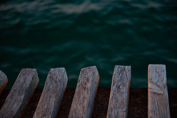 A wooden pier made of beams close-up extending into the ocean.