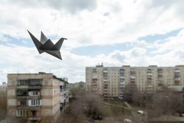 Paper origami bird cranes hanging on the window overlooking the street. Origami crane in Japanese...