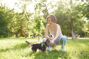 Obraz premium Woman owner with yorkshire terrier dog having fun on the grass. Puppy dog pet running with women for friends jog exercise, funny on the outdoor park, track and workout