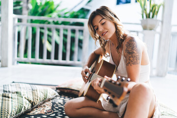 Woman playing acoustic guitar on terrace of hotel